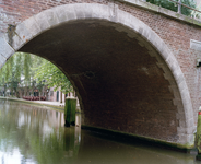 843695 Gezicht door een van de bogen van de Jacobibrug over de Oudegracht te Utrecht, voor de restauratie van de brug.